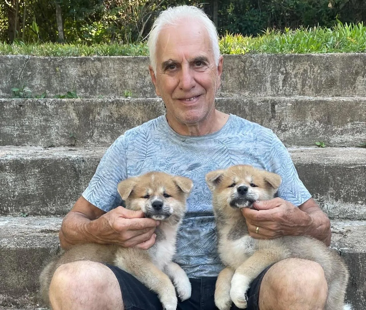 Vinícius, criador do Canil Tibiquary, segurando dois filhotes de Akita